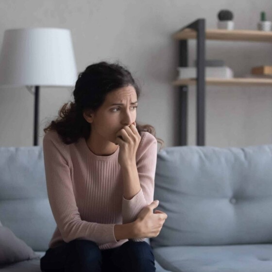 woman sat on sofa worried about chances of pregnancy after miscarriage